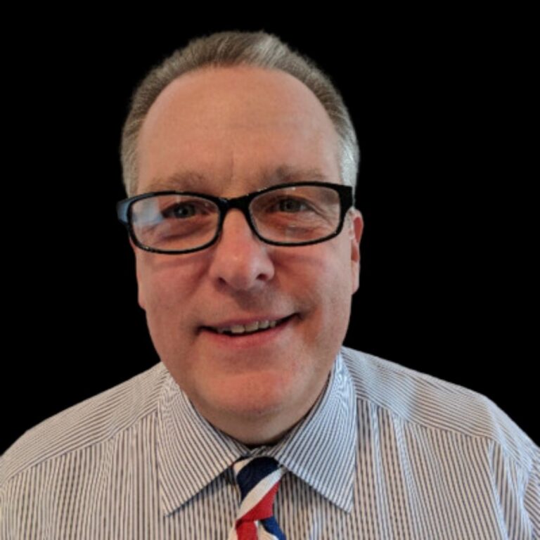 male with printed tie and grey shirt and glasses in black ground